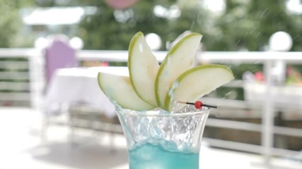 Slowmotion shot of bartender in outdoor restaurant terrace serving a summer cocktail with fruit. Cracked ice cubes falling into a glass. Food video. nutrition and drink concept. hd - Powered by Adobe