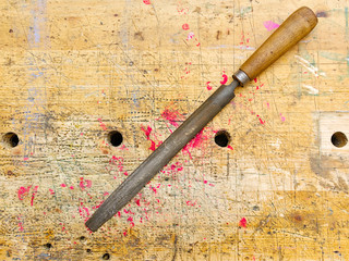 Rasp tool  isolated on aged wooden bench grunge surface with splash of red paint.
