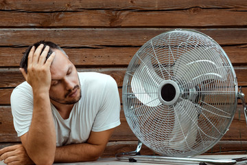 Sweaty man in front of a cooling ventilator, refreshing in the concept of hot summer. The concept...