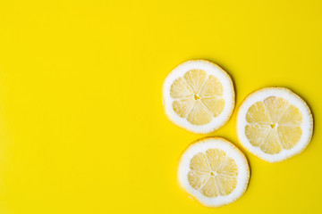 Three slices of lemon on a bright yellow background