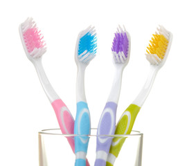 Multi-colored toothbrushes in a glass beaker on a white isolated background. Oral hygiene.