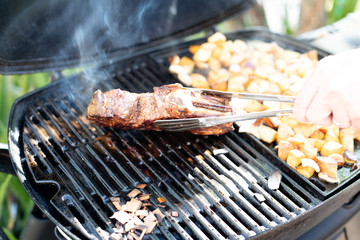 Steak and potato chunks cooking on a outdoor grill