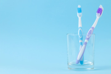 Oral hygiene. multi-colored toothbrush in a glass on a gentle blue background. space for text