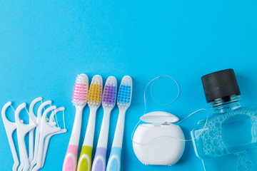 Oral hygiene. multicolored toothbrush, dental floss and mouthwash on a bright blue background. top...