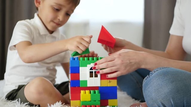 Close-up of the house from meccano. A happy family builds a house of colored blocks.
