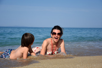 Mother and son enjoying on beach. Happy family relax on sea on summer vacation