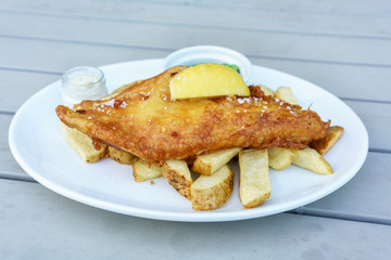 Homemade delicious North sea haddock in crispy batter , chips , green peas and tartar sauce
