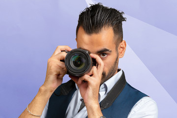 Fototapeta premium Young Arabian man using holding his camera ready to shoot, isolated
