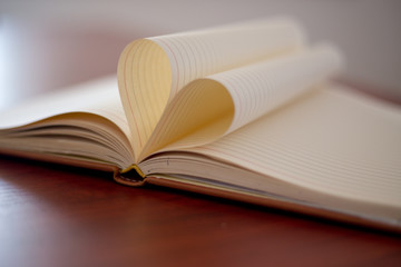 Heart from page of book concept with blurred bright light background and vintage tone
