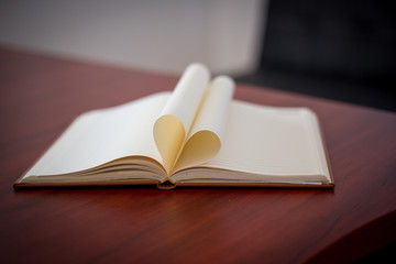 Heart from page of book concept with blurred bright light background and vintage tone