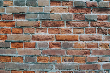 Urban wall from a red brick with a regular laying with scratched surface and grange stains.