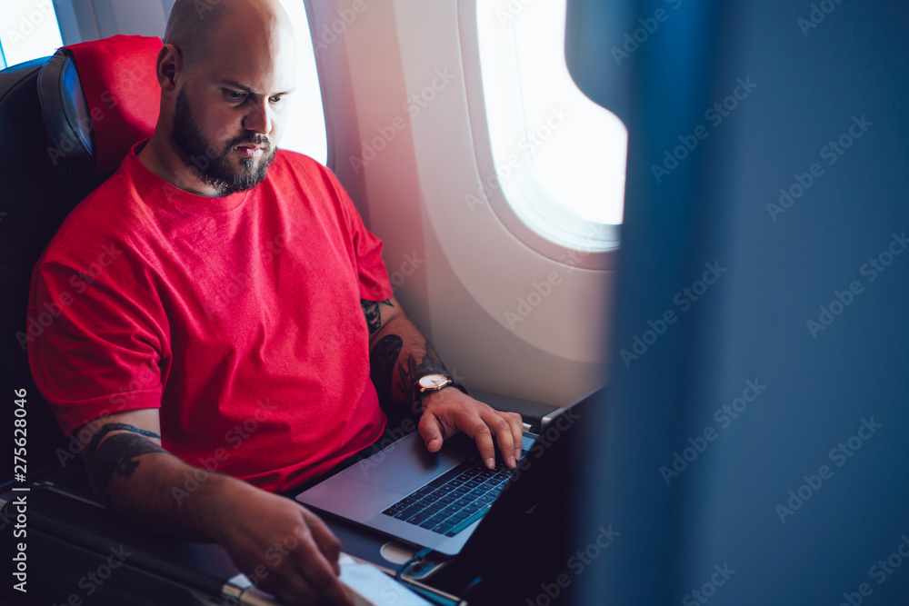 Poster caucasian man aircraft passenger sitting with tablet hands next to airplane window in business class