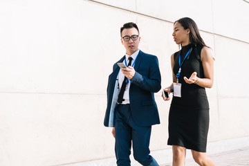 Communicating young business people with phone on street