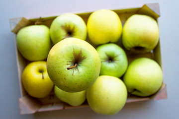 Green apples in a wooden crate. Concept- fresh organic fruit, healthy food from garden. Selective focus.