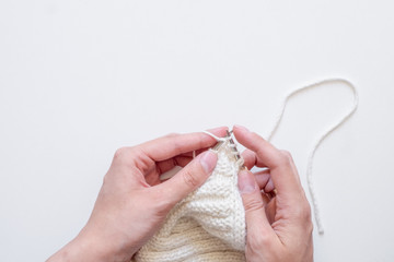 Obraz premium Hands knitting a sweater top view on white background