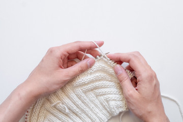 Hands knitting a sweater top view on white background