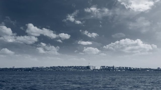 Cinemagraph landscape. Sky is full of moving clouds over the cityscape on the seashore. Looped video.