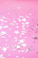 Silvery stars of different sizes on a pink background.