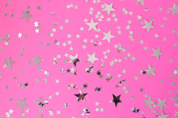 Fototapeta na wymiar Silvery stars of different sizes on a pink background.