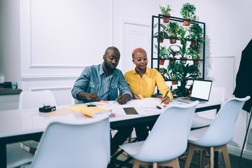 Obraz premium Black colleagues making notes in cafe