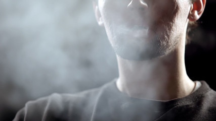 Man smoking electronic cigarette, bad habit causes skin problems, close-up