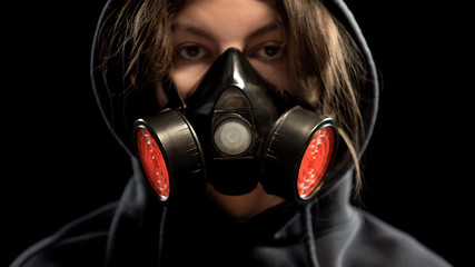 Female in respirator on dark background, protection from gas attack, closeup