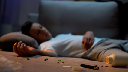 Teen boy sleeping at home, pills spilled on table, suicide attempt, depression - obrazy, fototapety, plakaty