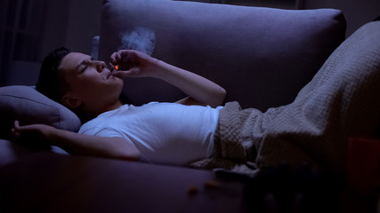 Teen student smoking in bed, lack of control, harmful addiction, dormitory