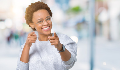 Young beautiful african american woman wearing glasses over isolated background pointing fingers to camera with happy and funny face. Good energy and vibes.