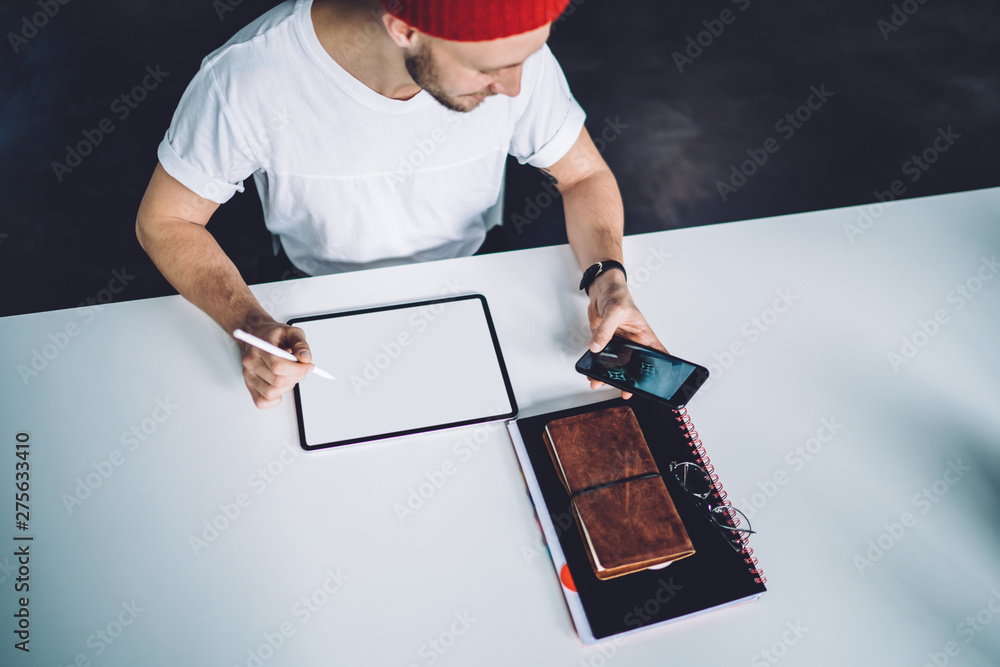 Poster top view of millennial hipster guy sitting at desktop with blank tablet with copy space area for art