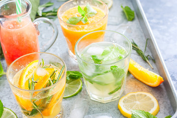Assorted summer cold citrus drinks on a metal tray, horizontal