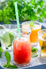 Cold grapefruit juice on a background of summer cold citrus drinks: mojito, lemonade, orange juice, tangerine juice, selective focus