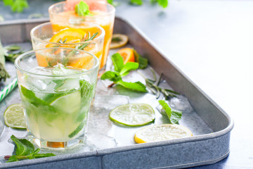 Assorted summer cold citrus drinks: lime, mandarin, orange, grapefruit, lemon on a metal tray, horizontal, copy space