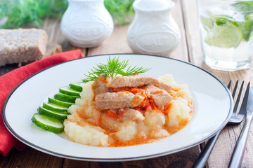 Pork slices with tomato sauce and mashed potatoes on a wooden table, horizontal