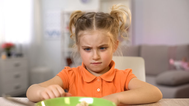 Girl refuse eating breakfast, pushing bowl away, healthy child nutrition