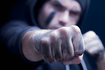Fototapeta na wymiar Close up aggressive man giving a punch. Robbery and konflict concept. Selective focus on fist.