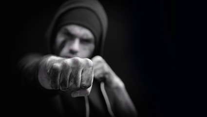 Portrait of aggressive man giving a punch. Robbery and konflict concept. Selective focus on fist. Black and white photo.