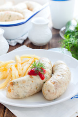 Homemade kupaty with chicken and french fries on a white plate, selective focus