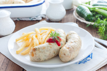 Homemade sausages with chicken and french fries on a white plate, horizontal