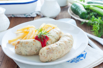 Homemade sausages with chicken and french fries on a white plate, horizontal