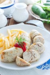 Homemade kupaty with chicken and french fries on a white plate, selective focus