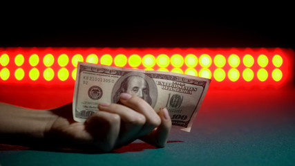 Hand showing 100 dollars on stage, concept of earnings in nightclub, closeup