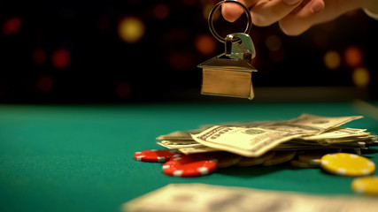 Risky poker player holding house keys, chips and money on table, all-in bet