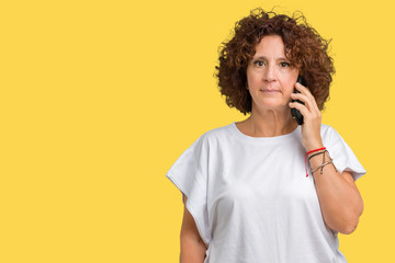 Middle ager senior woman talking on smartphone over isolated background with a confident expression...