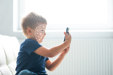 Little boy using face id authentication. Kid with a smartphone. Digital native children concept.