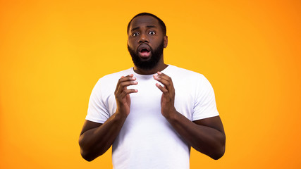 Scared afro-american man on bright background, shocking news, horror despair