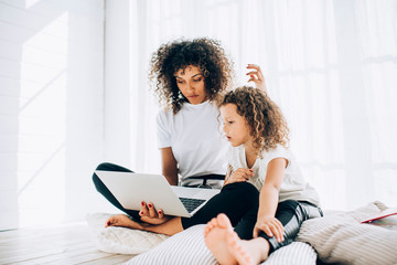 Relaxing woman with daughter using laptop in leisure