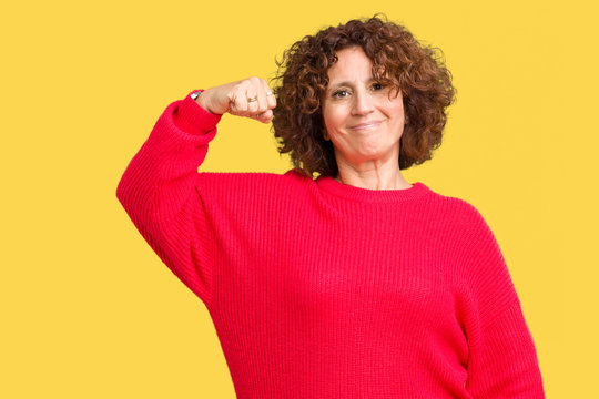 Beautiful middle ager senior woman red winter sweater over isolated background Strong person showing arm muscle, confident and proud of power
