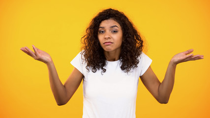 Afro-american female showing no idea gesture, unsure of choice, hesitation