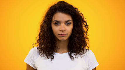 Angry black female looking in camera on bright background, disagreement feeling